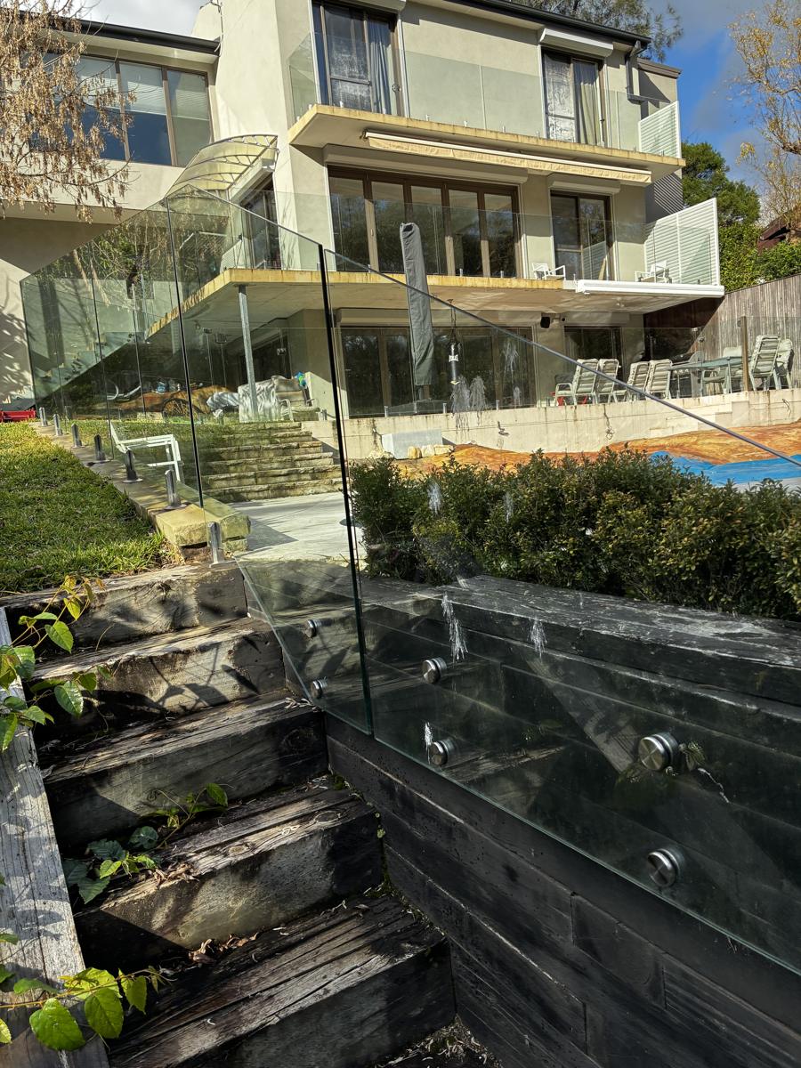 Glass pool fencing below a large home